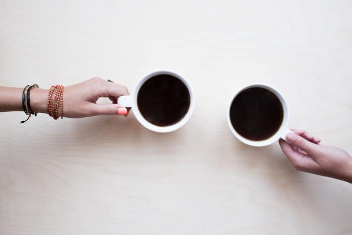 two people cheers cups of coffee