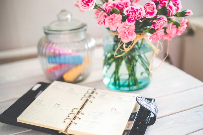 pink flowers next to a planner 