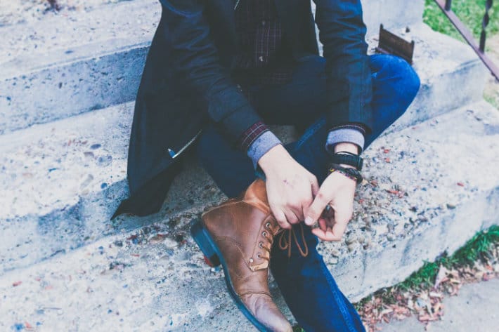 A man tying his shoes on steps.