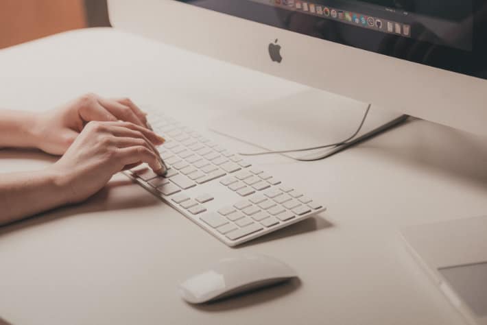 a person types on a keyboard at a Mac 