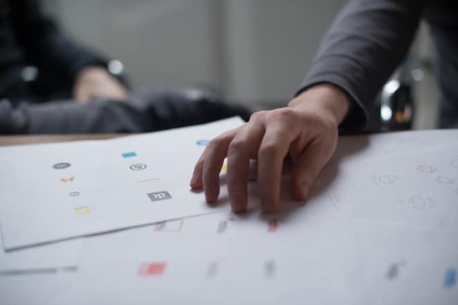 A person points to different logos on paper board.