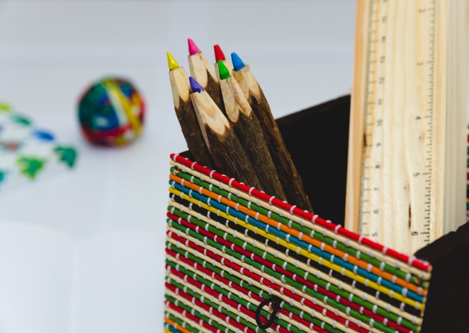 colored pencils in a colorful pencil holder alongside rulers and a rubber band ball