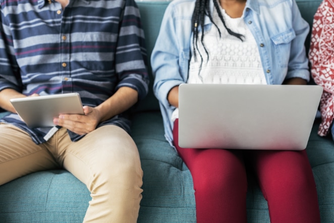 two people sit on a couch looking at a computer
