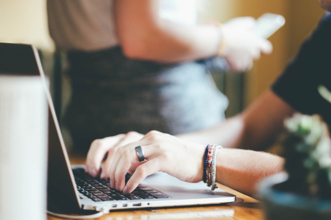 a person wearing multiple bracelets types on a laptop