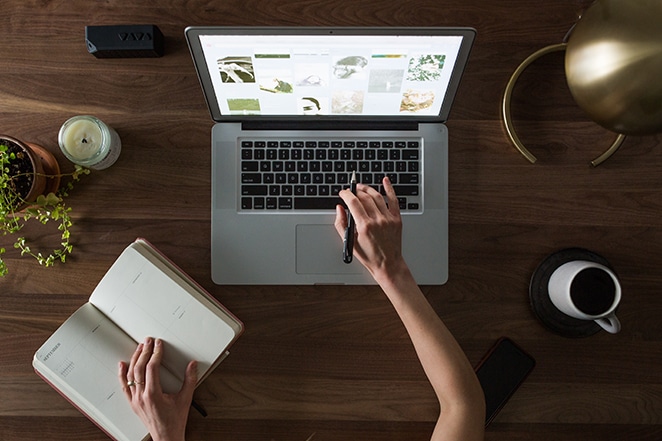 a person works on a laptop at a wooden desk