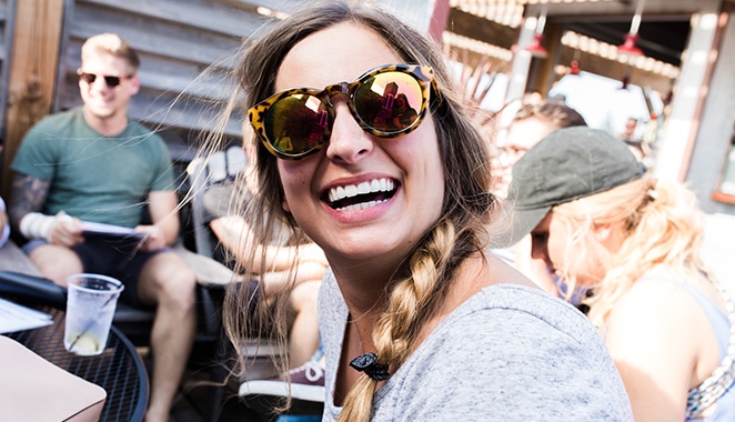 layout by flywheel designer's block woman in reflective sunglasses laughing among friends outdorrs