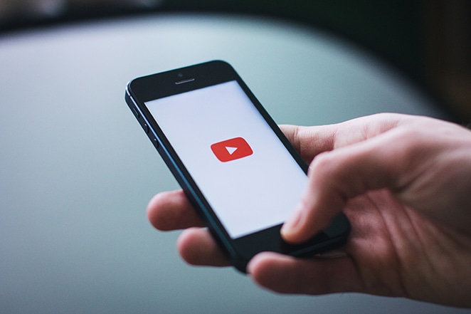 youtube logo loading on mobile phone in human hand