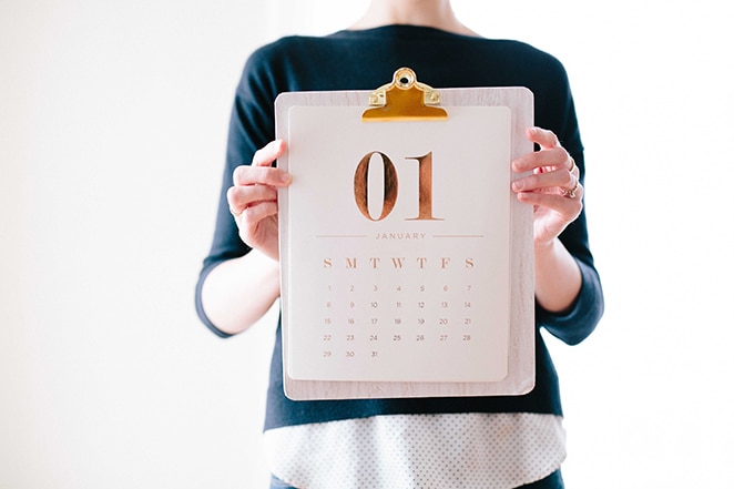 woman holding gold foiled calendar on clipboard