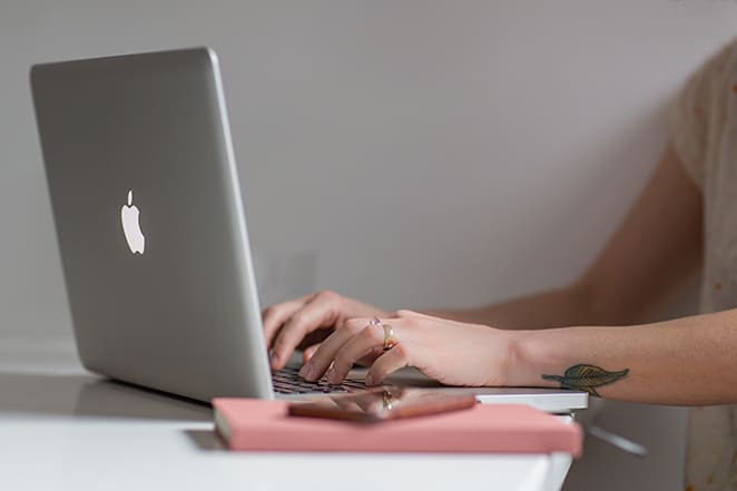 A professional in web design and digital marketing, distinguished by a unique leaf tattoo, skillfully executes tasks on her laptop.