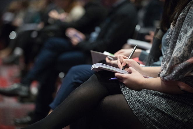 audience writing in notebooks