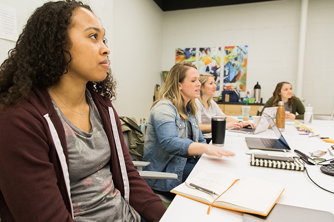 women sitting at table with notebooks and laptops in brainstorm