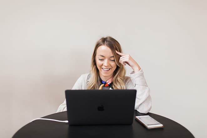 woman sitting at desk with computer thinking with finger pointed to brain