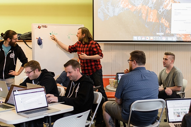 man teaching on white board to crowd