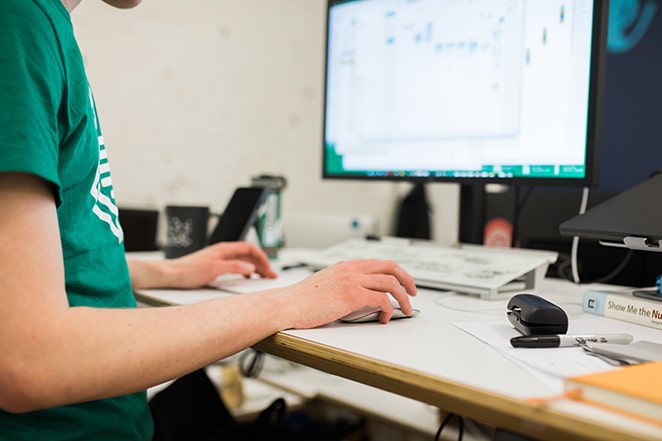 man at desk with hand on apple mouse by desktop