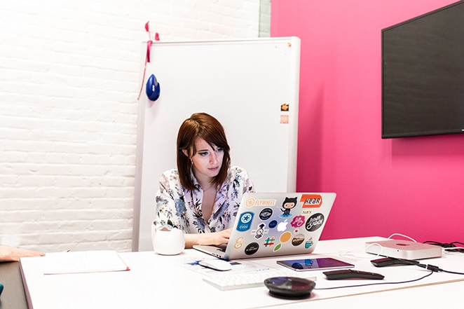 Web developer customizing WordPress post template on a laptop covered in stickers