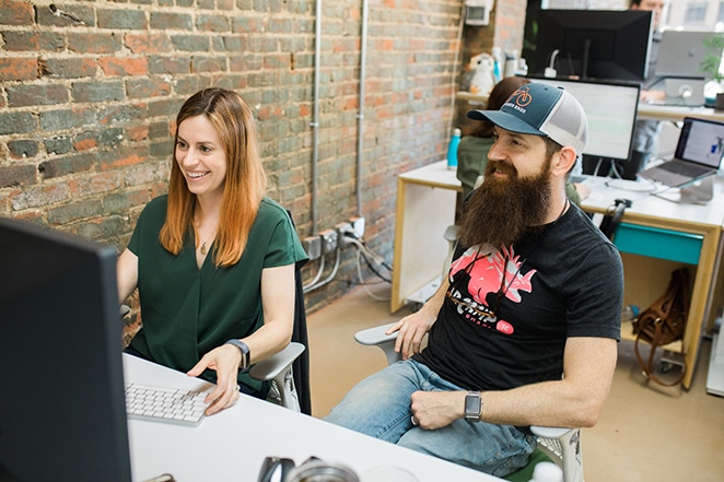 layout by flywheel how to clone your wordpress site man and woman sitting near desk and brick wall on desktop computer