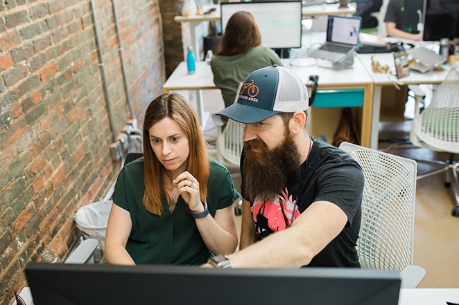 man pointing at screen and woman asking questions