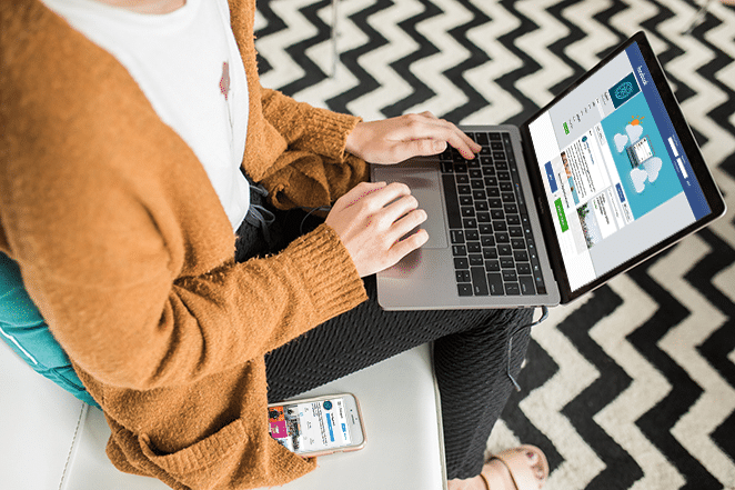 woman on couch with facebook on laptop and instagram on phone checking social media