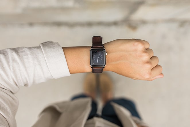 woman looking at apple watch with clock displayed checking her schedule