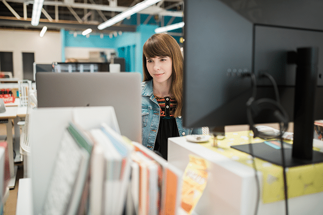 a person working on long-form content in wordpress between two screens with books in foreground