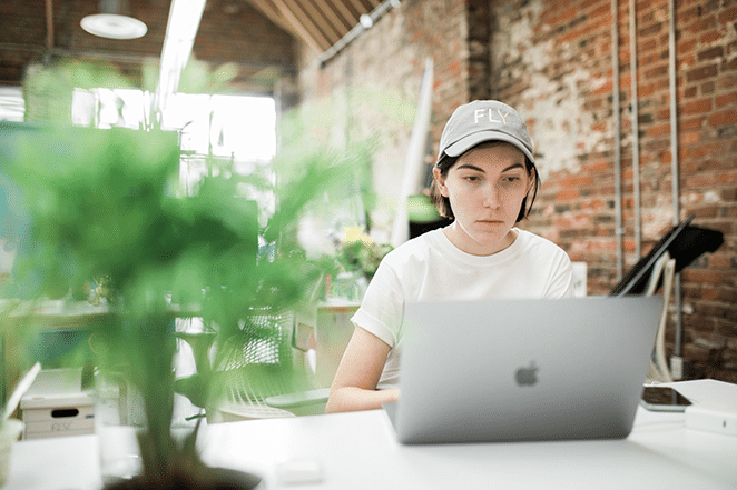 someone working on long-form article in wordpress on laptop with plant in foreground