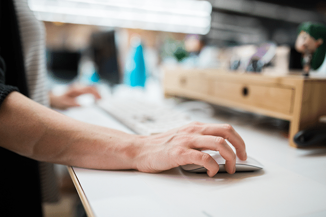 hand on mouse with desk scene in background working on long-form article in wordpress