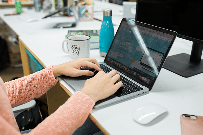 css variables and theme customizations feature woman typing on laptop with various scrum and design tools on white desk