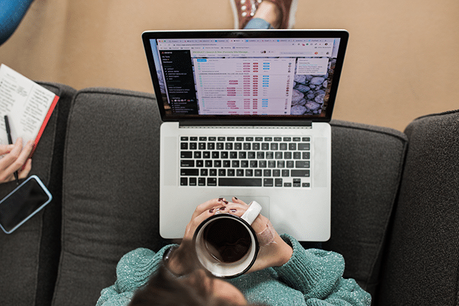 woman with coffee in hand and content metrics on laptop