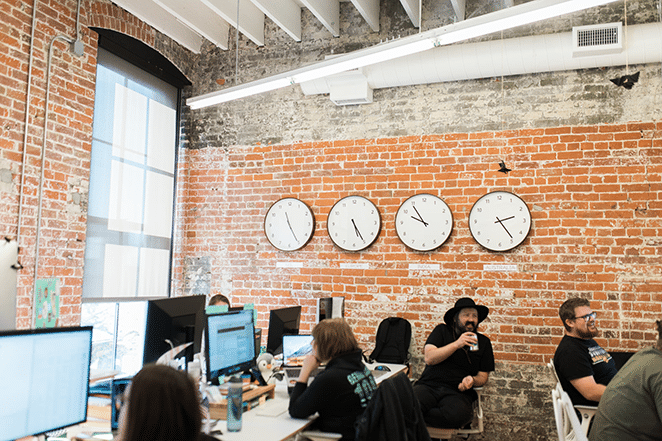 Clocks on a brick wall in an office.